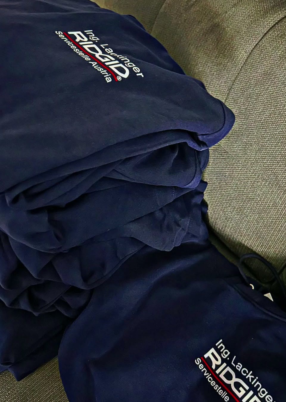 Stapel dunkelblauer Firmen-Sweater mit weißem Logodruck