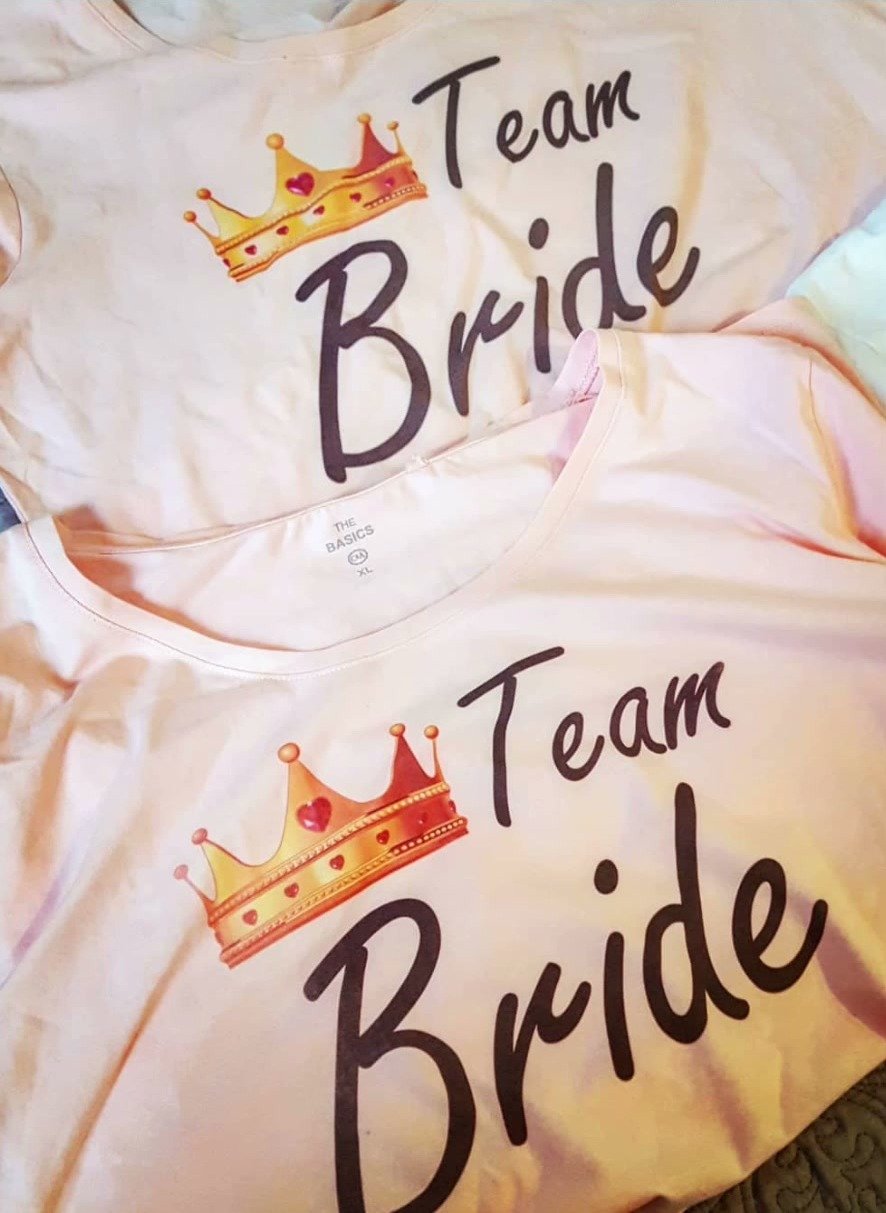 Zwei helle Shirts mit dem Aufdruck Team Bride und goldener Krone